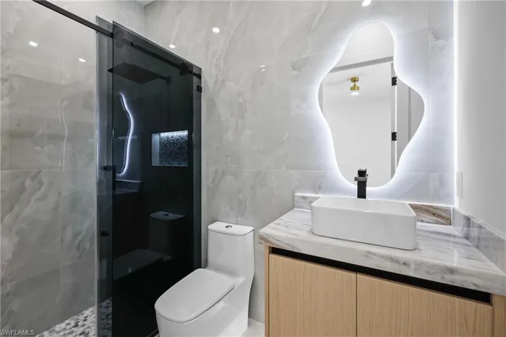 Full bath with tile walls, a stall shower, and vanity