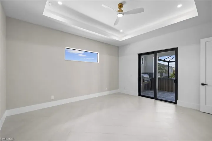 Spare room featuring a tray ceiling, healthy amount of natural light, a ceiling fan, and recessed lighting