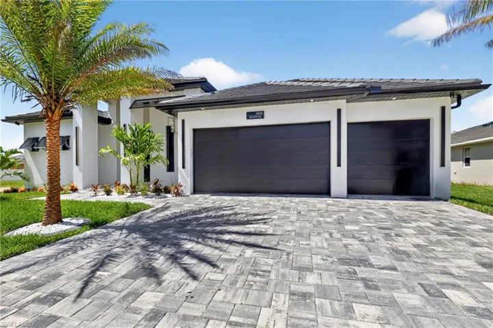 View of front of home with an attached garage, stucco siding, decorative driveway, and a tile roof