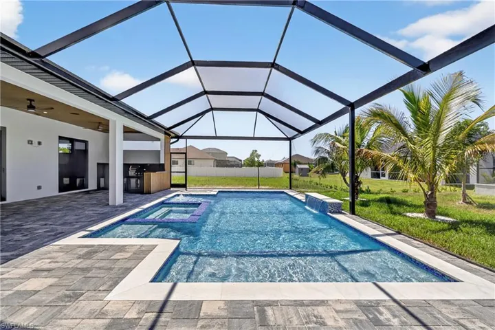 View of pool with an outdoor kitchen, a patio area, a yard, a ceiling fan, and a lanai