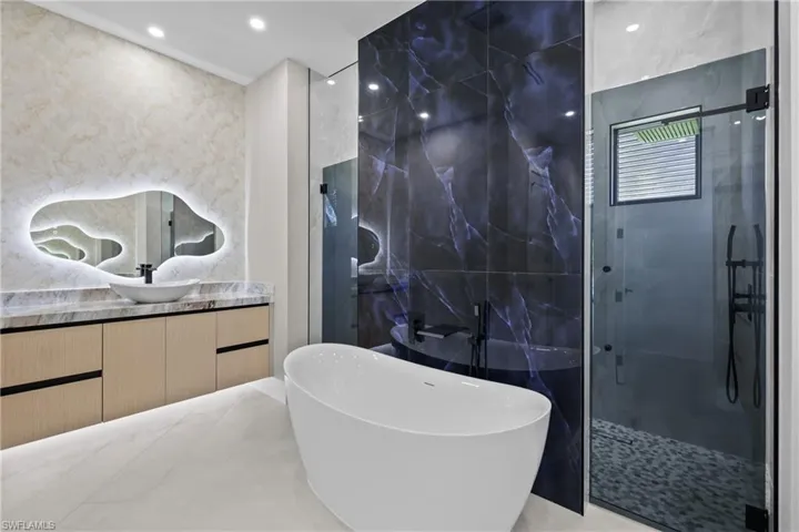 Bathroom featuring a shower stall, a freestanding bath, vanity, recessed lighting, and tile walls