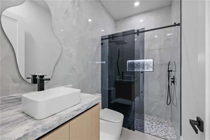 Full bathroom featuring tile walls, a marble finish shower, vanity, recessed lighting, and tile patterned flooring