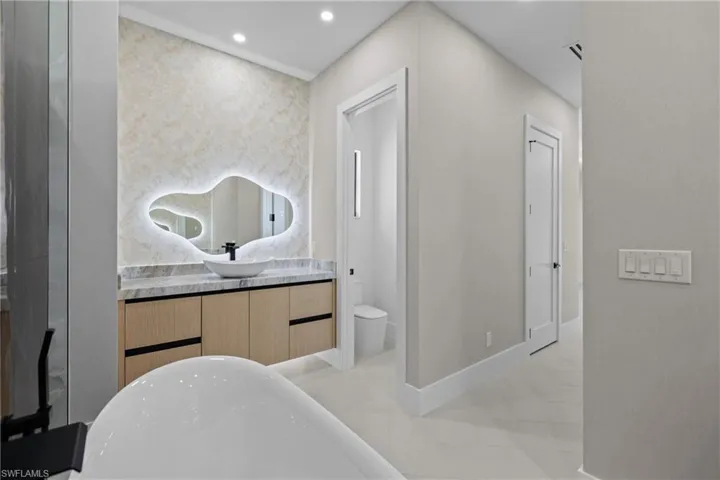 Bathroom featuring a soaking tub, vanity, recessed lighting, and tile patterned flooring