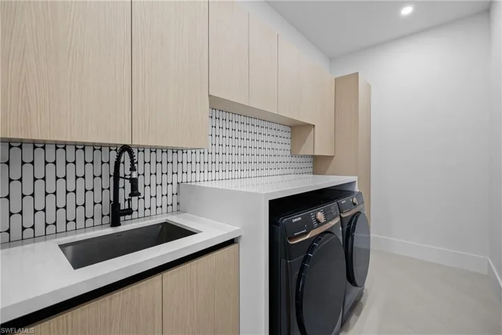 Laundry area featuring washing machine and dryer, recessed lighting, and light tile patterned floors