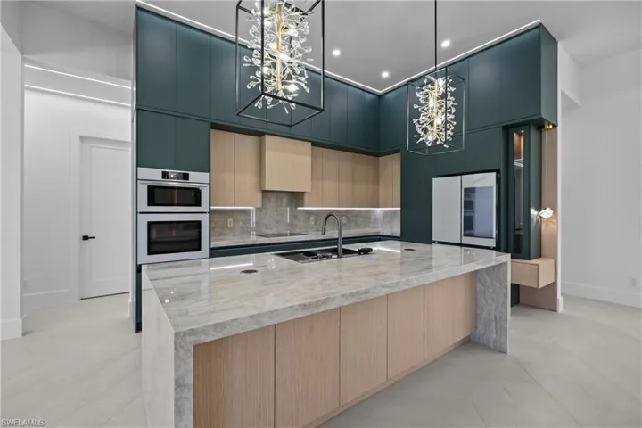 Kitchen with modern cabinets, backsplash, a spacious island, light stone countertops, and a high ceiling