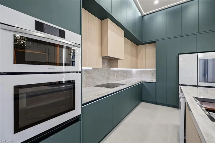 Kitchen with white double oven, tasteful backsplash, modern cabinets, and cooktop