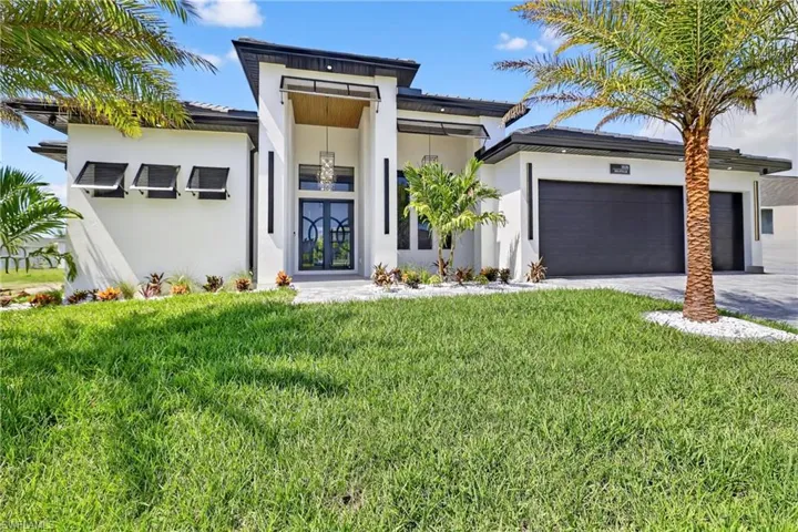 View of front of property with an attached garage, french doors, stucco siding, concrete driveway, and a front yard