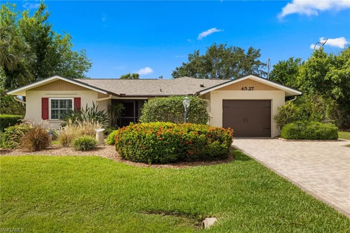 Single story home with driveway, an attached garage, a front lawn, and stucco siding