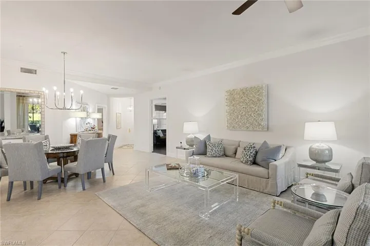 Living room with ornamental molding, a chandelier, and light tile patterned floors