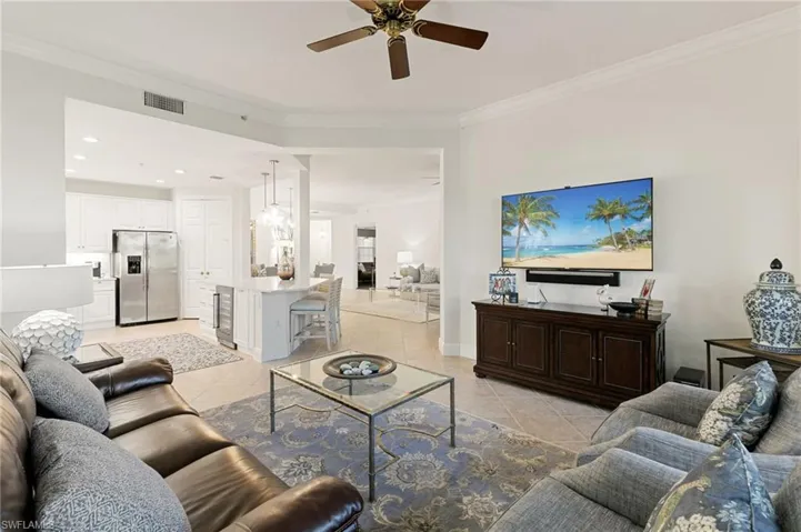 Living area featuring crown molding, light tile patterned flooring, ceiling fan, recessed lighting, and beverage cooler