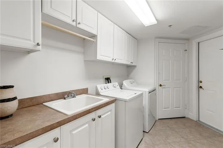 Washroom with cabinet space, washing machine and dryer, and light tile patterned floors