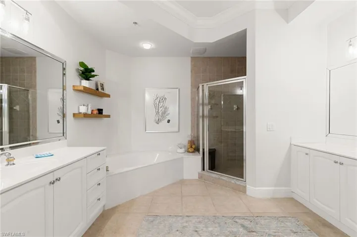 Bathroom with two vanities, ornamental molding, a bath, a shower stall, and light tile patterned floors