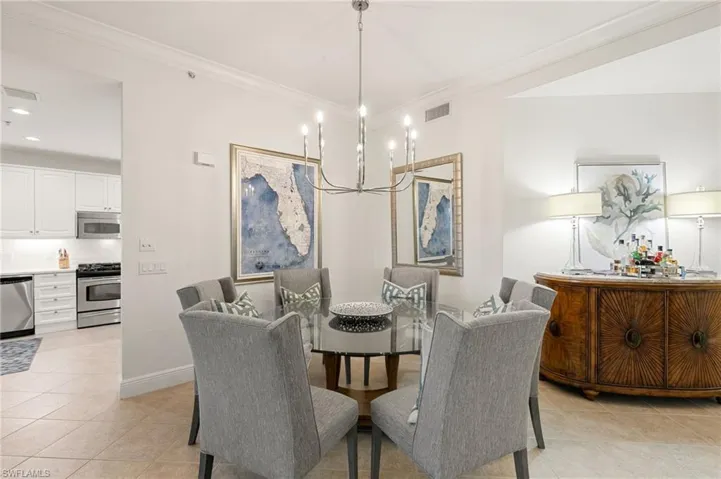 Dining room with light tile patterned floors, ornamental molding, recessed lighting, and a chandelier