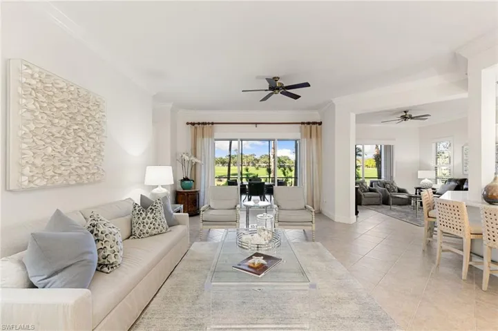 Living room with crown molding, light tile patterned flooring, and a ceiling fan