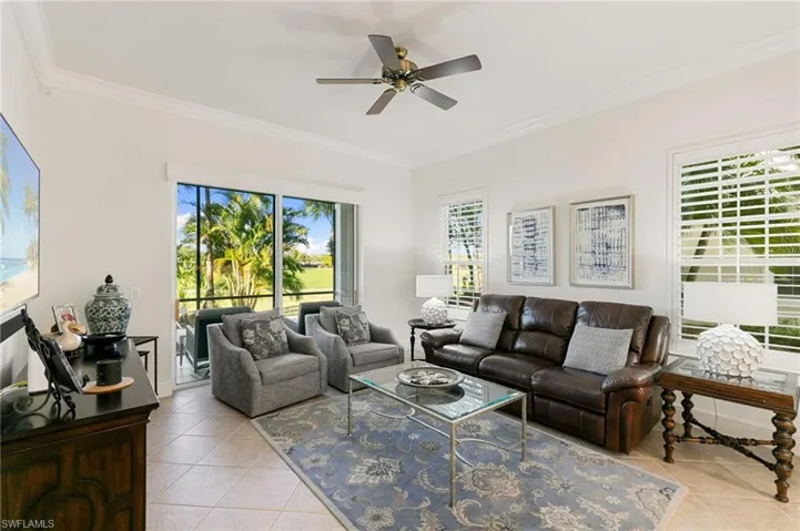 Living room with crown molding, healthy amount of natural light, light tile patterned floors, and ceiling fan