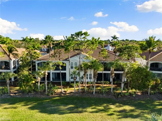 Back of house featuring a tiled roof, a lawn, and a sunroom