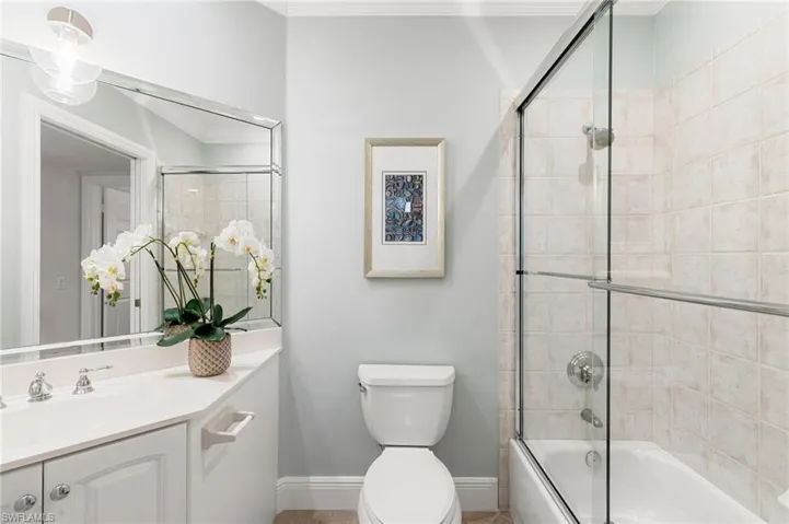 Full bathroom with enclosed tub / shower combo, ornamental molding, and vanity