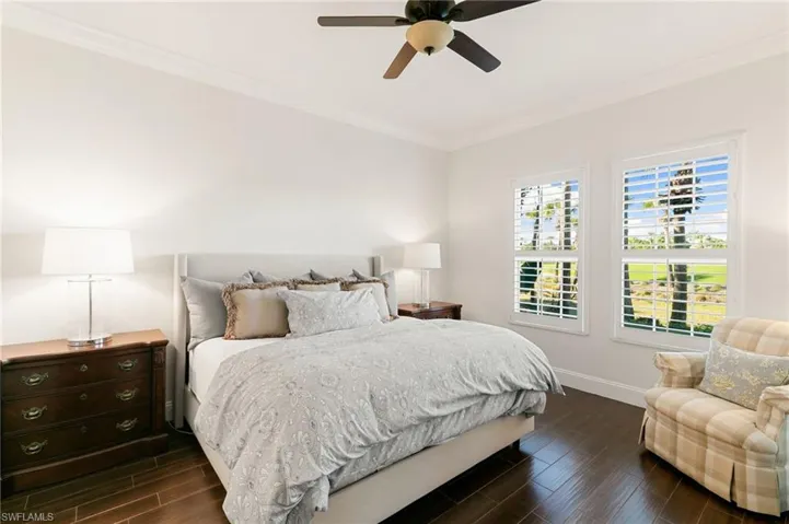 Bedroom with wood finish floors, ornamental molding, and ceiling fan
