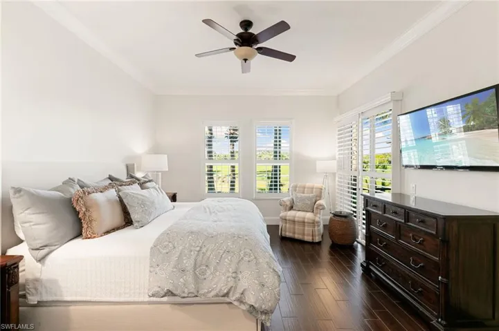 Bedroom with dark wood-type flooring, ornamental molding, and a ceiling fan