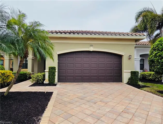View of front facade featuring a tile roof, stucco siding, decorative driveway, and a garage