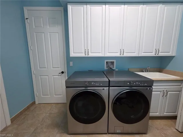 Laundry area featuring washer and clothes dryer, cabinet space, and light tile patterned flooring