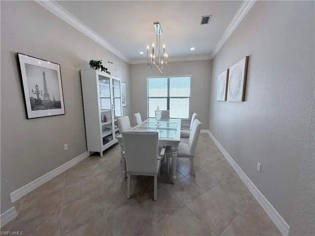 Dining area featuring crown molding, a chandelier, and a textured wall