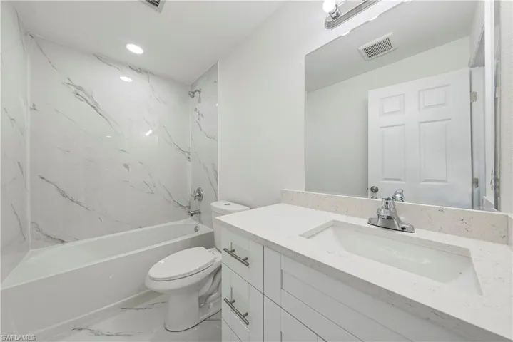 Full bathroom with tiled shower / bath, vanity, and toilet