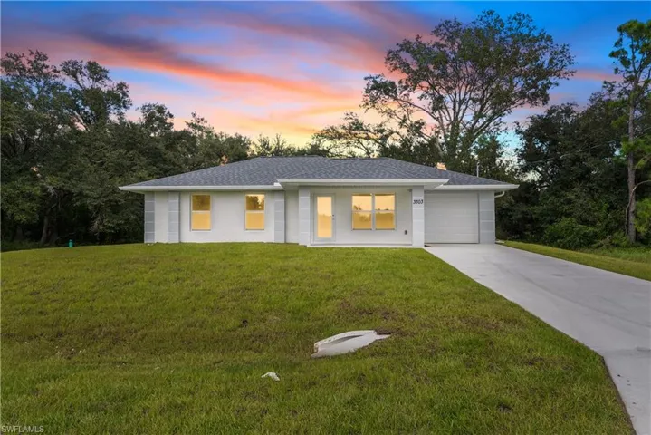 View of front of home featuring a garage, driveway, a lawn, and roof with shingles