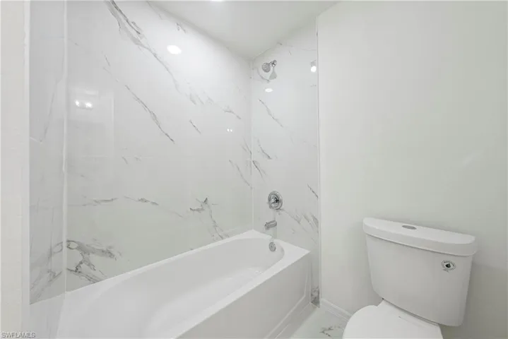 Bathroom with tiled shower / bath and toilet