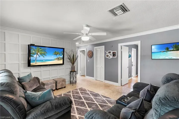 Living room with crown molding, ceiling fan, and a textured ceiling