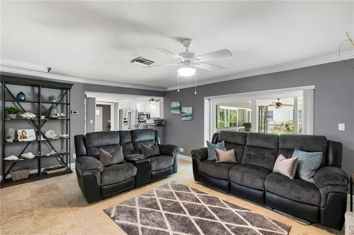 Living area featuring a ceiling fan, ornamental molding, and a textured ceiling