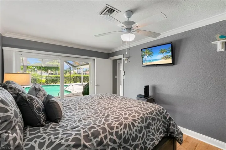 Bedroom with access to exterior, wood finished floors, a textured wall, ornamental molding, and ceiling fan
