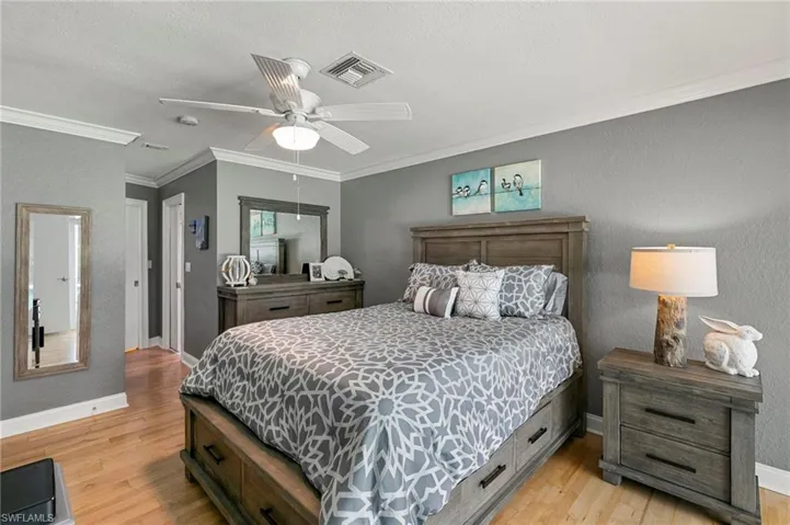 Bedroom featuring crown molding, light wood-style floors, and ceiling fan