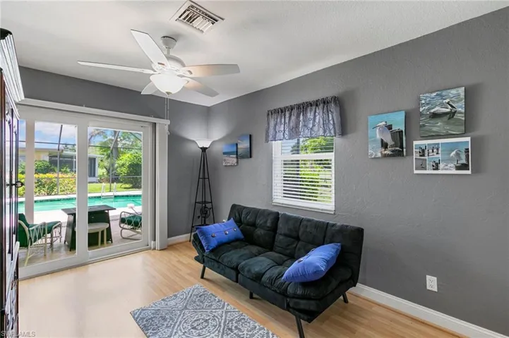 Living area with wood finished floors, ceiling fan, and a textured wall