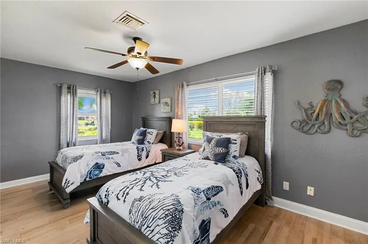 Bedroom featuring multiple windows, light wood finished floors, and a ceiling fan