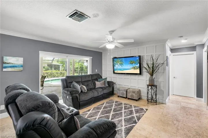 Living area with crown molding, a ceiling fan, and a textured ceiling