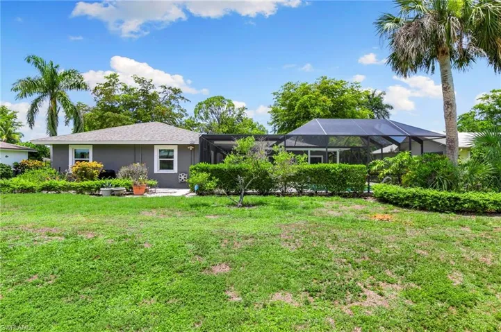 Back of property with a yard, stucco siding, and glass enclosure