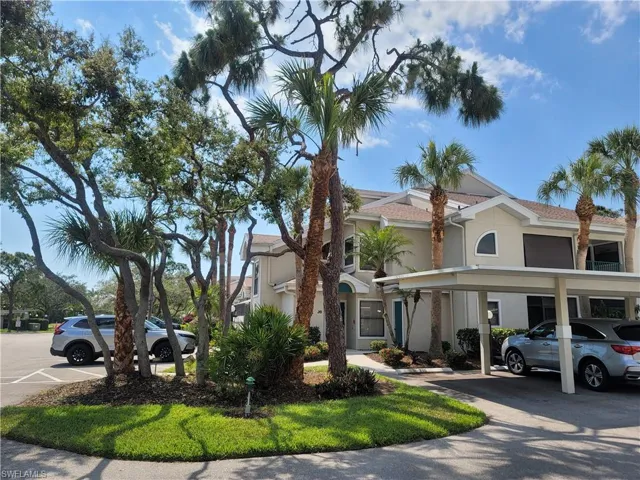 View of front of house featuring covered and uncovered parking and stucco siding