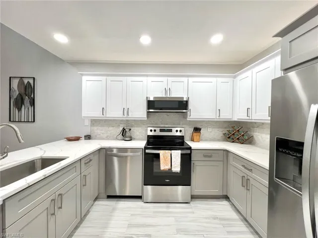 Kitchen featuring tasteful backsplash, gray cabinets, stainless steel appliances, and a sink