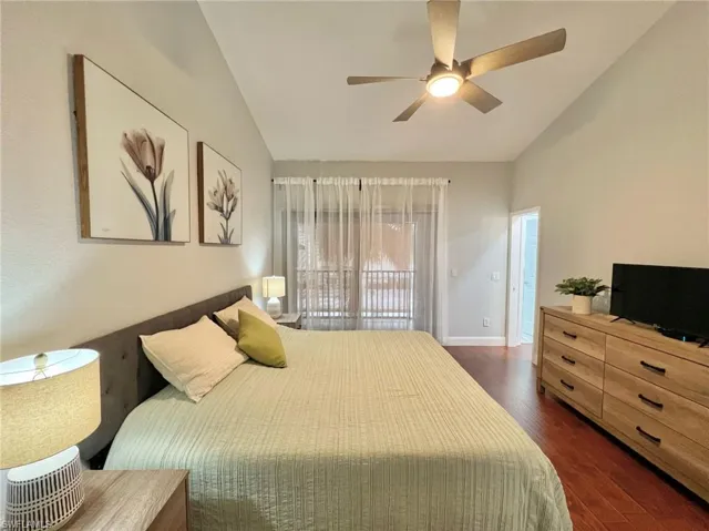 Master Bedroom with walk in closet, screened balcony, fan, lofted ceiling, and wood finished floors