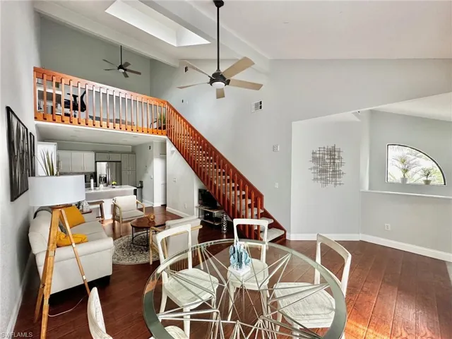 Dining room featuring visible vents, a ceiling fan, hardwood / wood-style flooring, baseboards, and stairs