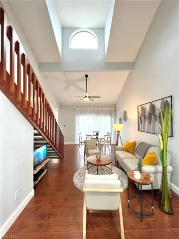 Living room with stairway, a ceiling fan, baseboards, and wood finished floors