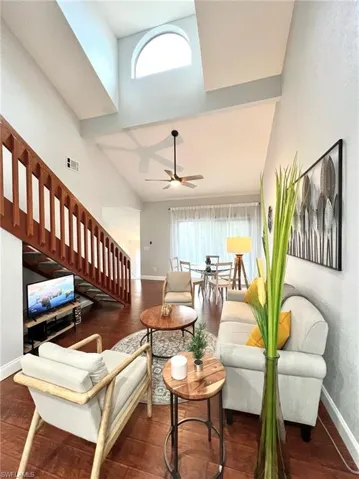 Living area with a healthy amount of sunlight, baseboards, stairs, and a high ceiling