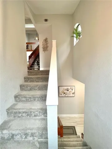 Entrance Stairway with visible vents, baseboards, ceiling fan, a high ceiling, and wood finished floors