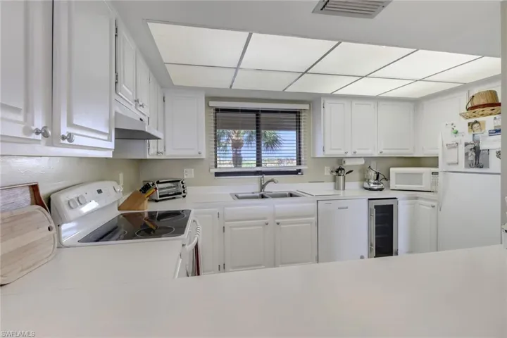 Kitchen featuring wine cooler, white cabinetry, white appliances, and sink