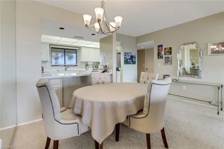 Carpeted dining space featuring a notable chandelier and sink