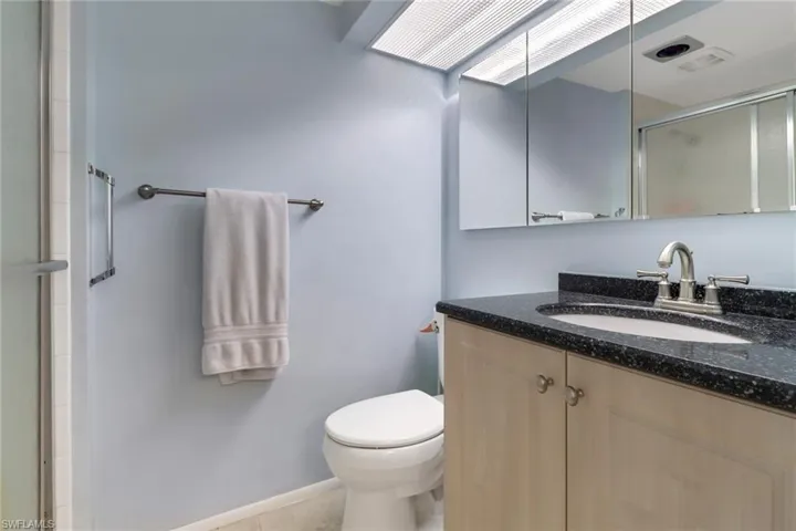 Bathroom featuring toilet, vanity, tile patterned floors, and a shower with shower door