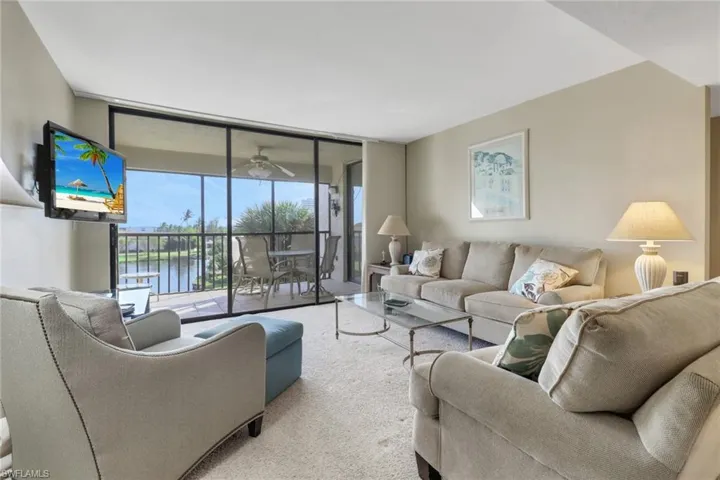 Carpeted living room featuring ceiling fan and floor to ceiling windows