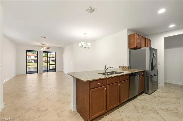 Kitchen featuring dark stone counters, pendant lighting, a peninsula, light tile patterned floors, and open floor plan