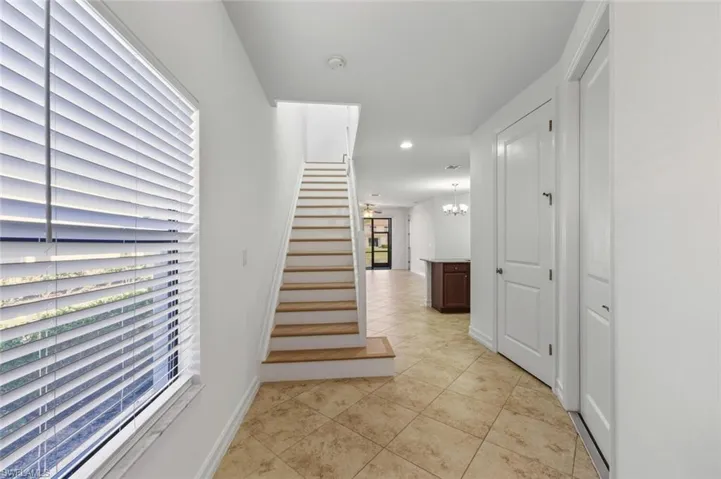 Hall featuring stairway, a chandelier, and light tile patterned floors